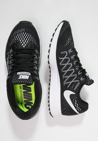 Baskets de course en mesh noir avec des accents blancs, dotées d'une tige respirante, d'une semelle rembourrée et d'un motif de semelle texturé.