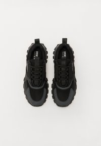 Baskets de sport noires avec une tige en maille et synthétique, dotées d'une semelle épaisse, d'un bout rond et d'accents texturés. Cordon de lacet inclus.