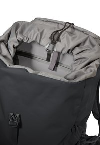 Ouverture supérieure d'un sac à dos gris avec fermeture à cordon de serrage et poche intérieure zippée, montrant la texture du tissu et une boucle noire à l'avant.