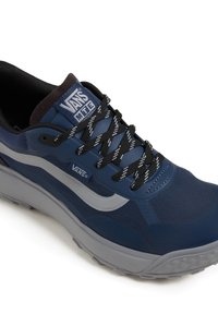 Baskets Vans MTE bleu marine avec des lacets noir et blanc, bande blanche sur le côté, semelle épaisse grise et col rembourré noir.