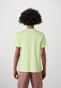 Light green cotton t-shirt with a crew neck and short sleeves, featuring a smooth texture and a relaxed fit, viewed from behind.