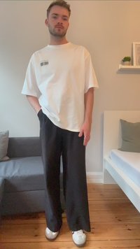 Weißes, übergroßes T-Shirt mit einem Barcode-Graphic, kombiniert mit schwarzen weiten Hose und weißen Sneakern. Lässiger Lounge-Stil.
