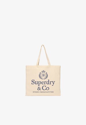 Beżowa torba na ramię z cienkimi uchwytami i "Superdry & Co Authentic Premium Outfitters" nadrukowanym na niebiesko z ozdobnym herbem nad tekstem.