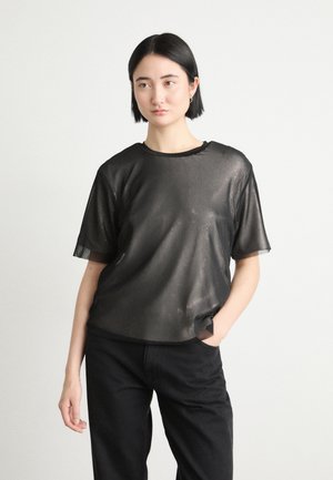 Haut noir à manches courtes en tissu en mesh transparent, doté d'un col rond et d'une coupe décontractée, associé à un pantalon sombre.