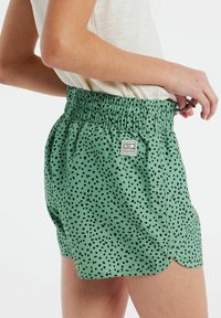 Groene shorts met een zwart stippenpatroon, voorzien van een elastische tailleband en een klein logo label. Glad materiaal met een lichtgewicht ontwerp.