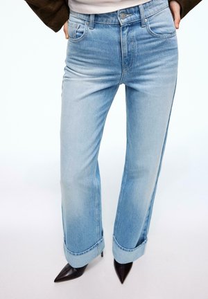 Jean denim bleu clair à jambes larges avec ourlets retournés, présentant une texture lisse, une décoloration subtile et un design classique à cinq poches.