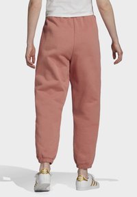 Rosa mjukisbyxor i mjukt tyg, med avslappnad passform, smalnande muddar och elastisk midja. Bärs med vita sneakers.