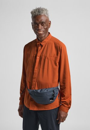 Camicia arancione con bottoni e maniche lunghe, accompagnata da una borsa a tracolla grigia. La camicia presenta una texture liscia. La borsa è dotata di zip e di un logo.