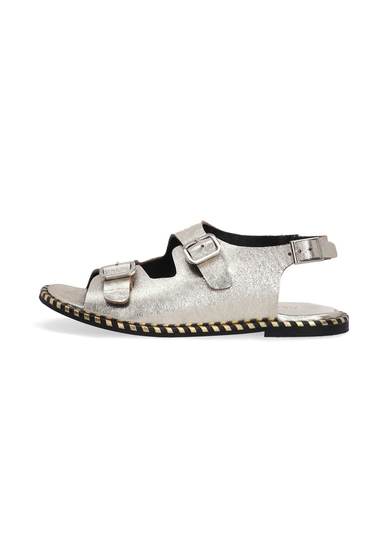 Zilveren metalen sandalen met een open teen, twee verstelbare gespbanden en een gevlochten zwarte en gouden zool. Platte vormgeving met minimale bedekking.