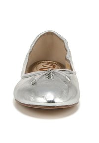 Ballerine argentée avec une finition métallique texturée, bord élastique et nœud décoratif avec des accents métalliques argentés.