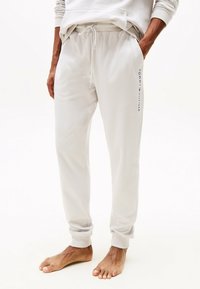 Hellgraue Jogginghose mit elastischem Bund und Kordelzug. Sie verfügt über seitliche Taschen und dezente "Tommy Hilfiger"-Markenkennzeichnung am Bein.