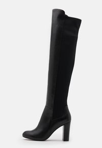Botas negras hasta la rodilla con un acabado de cuero suave y tejido texturizado. Cuentan con un chunky tacón de bloque transparente.
