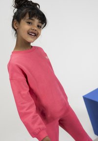 Roze fleece sweatshirt en bijpassende broek met een ronde hals en geribbelde boorden. Zachte textuur, voorzien van een klein gouden logo-detail.