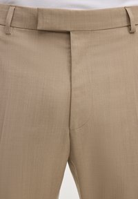 Beige, maßgeschneiderte Hose mit Bundschlaufen, verdecktem Reißverschluss vorne und glatter Stoffstruktur.