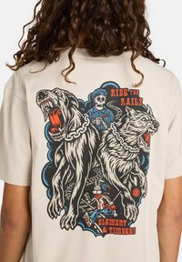 Dva agresivní psi na řetězech vrčí, za nimi je kostlivý dirigent a kreslený králík běží podél železničních kolejí. Text říká „Jízda po kolejích.“