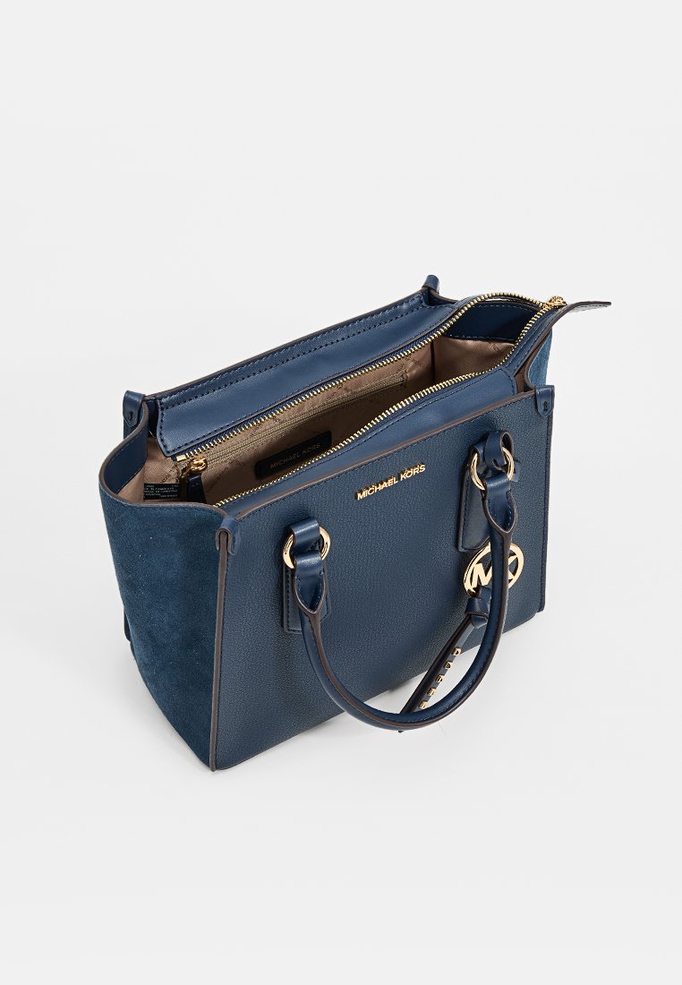 Borsa Michael Kors blu navy con hardware dorato, due manici, scomparto principale con zip e pannelli laterali in camoscio.