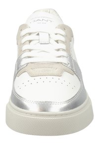 Weiße Sneaker mit silbernen Metallakzenten, ausgestattet mit einer Wildleder-Zehenkappe, durchgehendem Design, flachen Schnürsenkeln und einer strukturierten Gummi-Sohle.