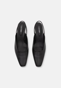 Sorte slingback-sko med firkantet tådesign. Laget av glatt skinn, med minimalistisk stil og en merket såle.