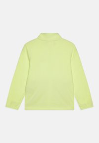 Polo à manches longues de couleur jaune néon vif, fabriqué dans un matériau lisse. Dispose d'un col classique et d'une coupe décontractée avec un ourlet droit.