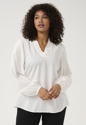 Witte, textuurblouse met een gerimpelde V-hals en volumineuze mouwen, gecombineerd met een zwarte broek. Stevige stof en een relaxed fit.