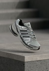 Gray running shoe with mesh upper, black accents, and textured sole. Features reflective details and a padded collar for comfort.