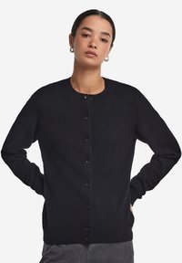 Czarny kardigan z okrągłym dekoltem, długimi rękawami i zapięciem na guziki. Wykonany z miękkiego materiału z prążkowanymi mankietami i dołem.