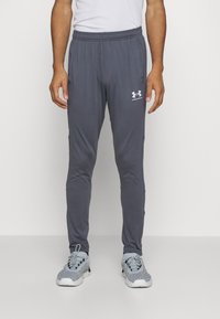 Pilki sportiniai džinsai su elastingu juosmeniu, siaurėjančiomis kojomis ir šoninėmis kišenėmis. Yra mažas baltas „Under Armour“ logotipas kairiajame šlaunyje.