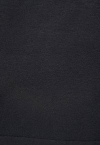 Černá bavlněná tkanina s hladkou strukturou, která má žebrovaný pletený vzor a jednotnou barvu v celém materiálu.