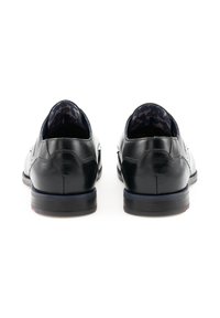 Chaussures noires en cuir avec une finition lisse, forme arrondie, profil bas et doublure intérieure en navire texturée. Des détails de couture subtils accentuent le design.