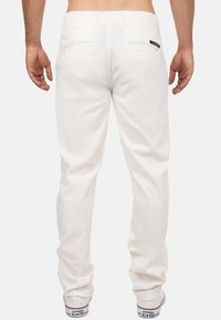 Witte katoenen broeken met een rechte pijpdesign. Voorzien van achterzakken en riemlussen. Gecombineerd met witte sneakers.