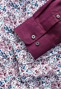 Kvetinová košeľa s bielym podkladom a modrými a burgundskými vzormi; burgundové manžety so striebornými gombíkmi; hladká textúra a prispôsobený strih.