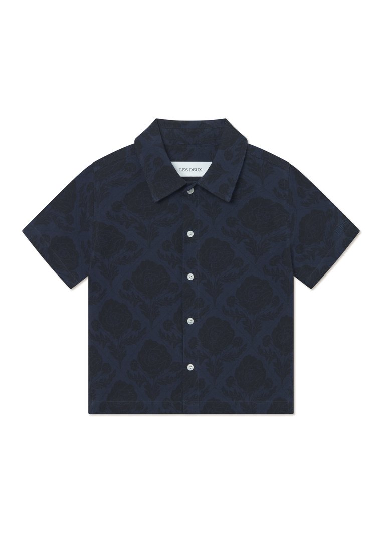 Korte ermerskjorte i marineblått stoff med blomsterdesign, med krage og frontlukking med knapper. Knapper er hvite.
