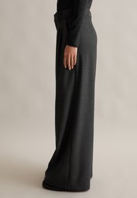 Hooggetailleerde, wijde broek in donkergrijze stof, met voorplooien en een gedefinieerde tailleband met knoopsluiting.