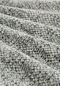 Tissu texturé en noir et blanc, présentant un motif tissé avec des couleurs alternées, affichant épaisseur et douceur.
