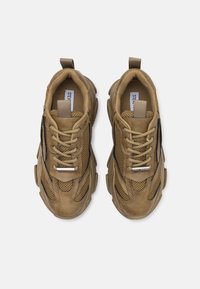 Paire de baskets épaisses marron en mesh et daim avec des semelles épaisses et des lacets beiges, vues de dessus sur fond blanc.