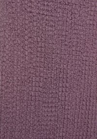 Gros plan sur un tissu mauve avec un motif tissé texturé de boucles arrondies en relief créant une surface en forme de grille.