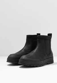 Černé kožené chelsea boty s hladkým povrchem, elastickými bočními panely a gumovými podrážkami s texturovaným vzorem.