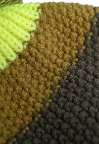 Textured fabric featuring vibrant green, brown, and dark gray sections, with a woven pattern and distinct color blocks.