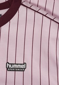 Rosa sporttröja med tunna mörk-maroon vertikala ränder, ribbad halsringning och en logotags som läser "hummel SPORTSWEAR" i svart.