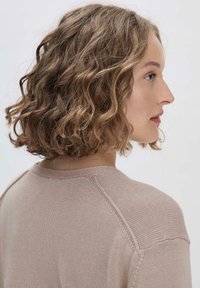 Strickpullover in sanftem Rosa mit rundem Halsausschnitt, strukturiertem Gewebe und Raglanärmel, der eine lockere Silhouette und einen subtilen Glanz zeigt.