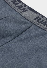 Šedoblévé pánské spodní prádlo z měkké, texturované tkaniny. Obsahuje tmavý pas s logem "MAN" v kontrastních barvách.