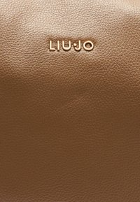 Borsa in pelle color cuoio con superficie testurizzata e un prominente logo dorato "LIU JO". Design pulito senza hardware o decorazioni visibili.