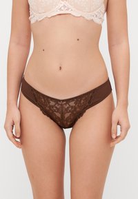Mutande in pizzo marrone con un motivo floreale e dettagli in mesh trasparente. Tessuto morbido, design a vita bassa, con un accento sulla cintura.