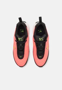 Pink and black sneakers with a textured upper, featuring a lacing system, neon green accents, and a cushioned white sole.