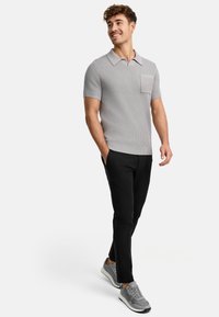 Graues geripptes Poloshirt mit kurzen Ärmeln, mit Kragen und einer Brusttasche. Kombiniert mit schwarzen Slim-Fit-Hosen und grauen Sneakers.