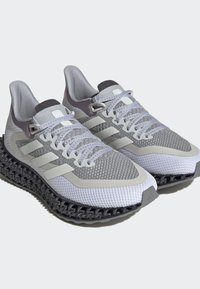 Scarpe sportive in rete grigia con tre strisce bianche. Sole nero texturizzato notevole, accenti a contrasto e chiusura con lacci.