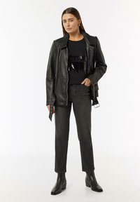 Black leather biker jacket, fitted black sequined t-shirt, dark gray straight-leg jeans, and black heeled ankle boots. Simple design, no patterns.