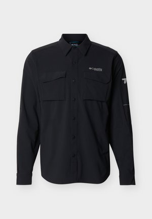 Chemise noire à manches longues avec boutons, deux poches à rabat sur la poitrine, col, et logo "Columbia Titanium" sur le côté gauche de la poitrine ainsi qu'un logo sur la manche droite.