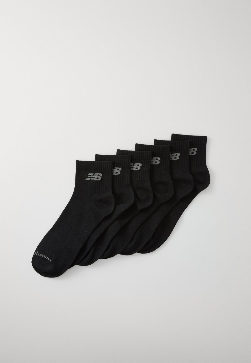 Calcetines de algodón negros organizados en una pila, con un diseño acanalado y el logotipo visible de New Balance en gris en la parte superior.