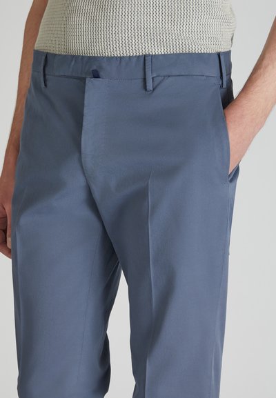 Helleblaue, maßgeschneiderte Hose aus glattem Stoff, mit seitlichen Taschen und einem flachen Frontdesign mit dezenten Nähdetails.